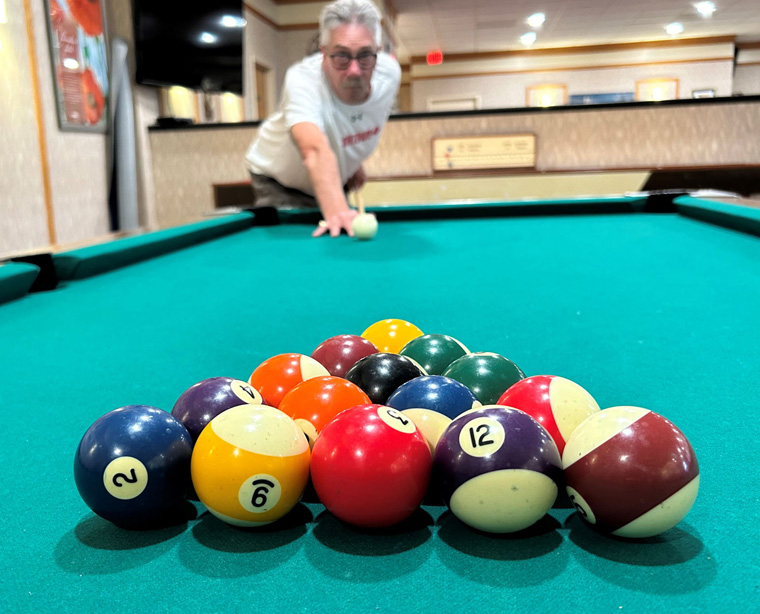 Image of a man in front of a rack of pool balls on a pool table ready to break