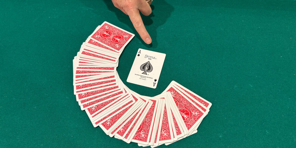 Image of a card deck with a finger pointing at the Ace of Spades